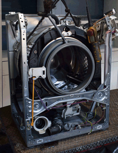 Miele wasmachine open in de werkplaats, de trommel wordt met een takel uit de machine getild